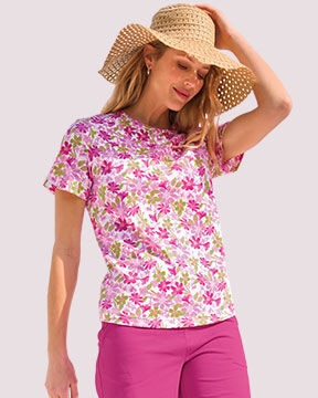 model wearing pink pants and pink floral top, with a tan hat