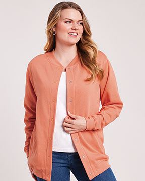 smiling woman wearing orange knit jacket with white t-shirt and blue jeans
